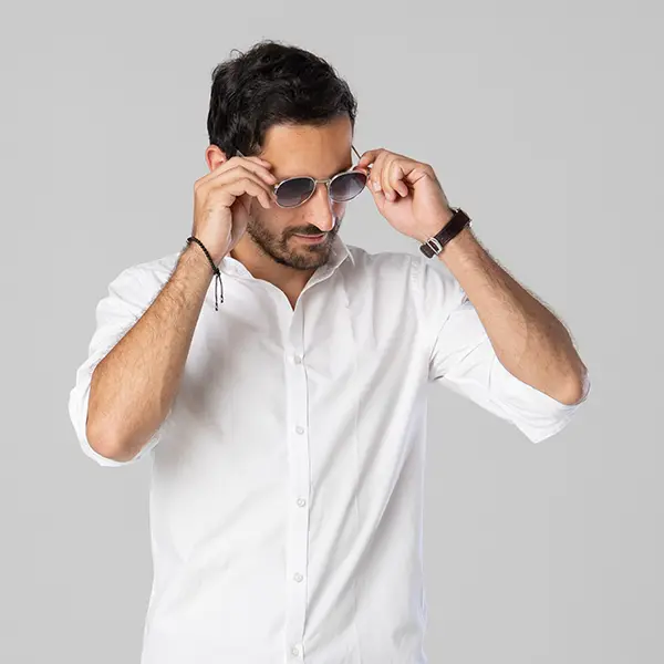 Modernes Portraitshooting in Zofingen mit Mann im weissen Hemd und Sonnenbrille vor hellem Studiohintergrund.