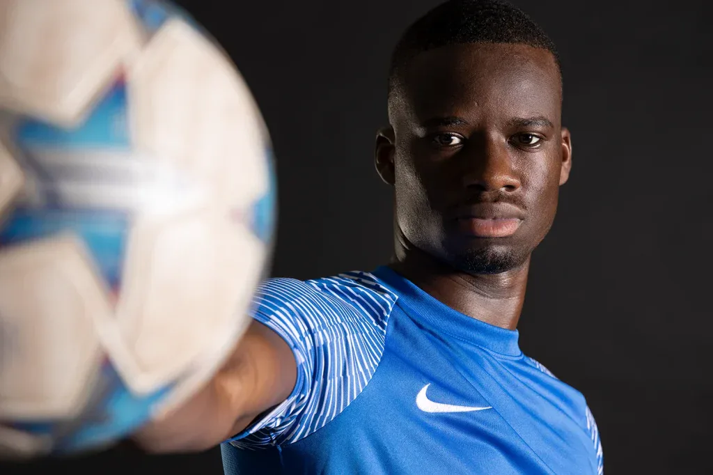 Sportliches Portraitshooting in Zofingen mit Fussballspieler vor dunklem Studiohintergrund und dynamischer Bildwirkung.