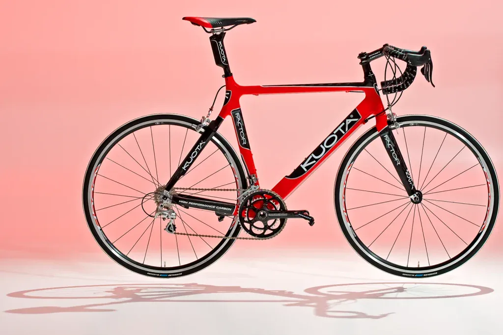 Rotes Rennvelo als freigestellte Werbeaufnahme vor einem dezenten rosa Hintergrund.