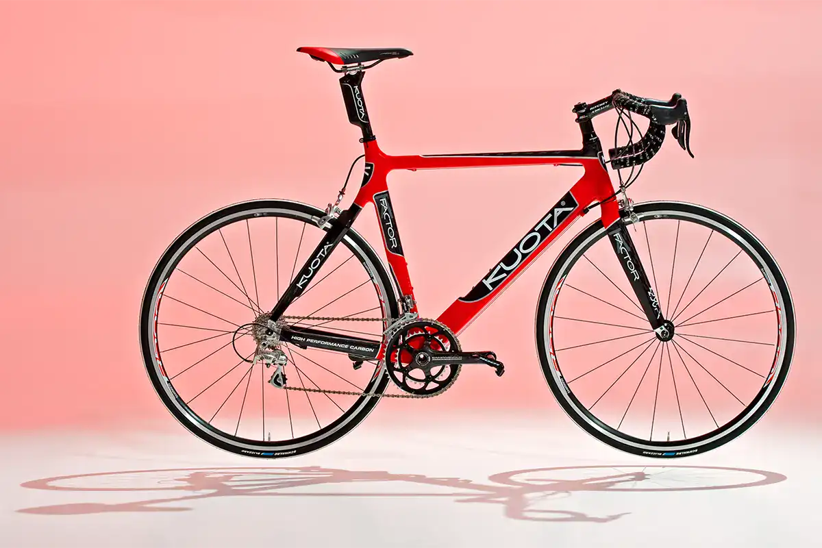 Rotes Carbon-Rennvelo als professionelle Produktfotografie vor einem rosa Studiohintergrund.