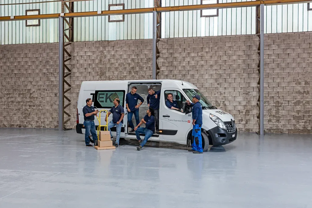 Teamfoto eines Handwerksbetriebs mit Servicefahrzeug in einer Werkhalle für Firmenpräsentation und Mitarbeitersuche.