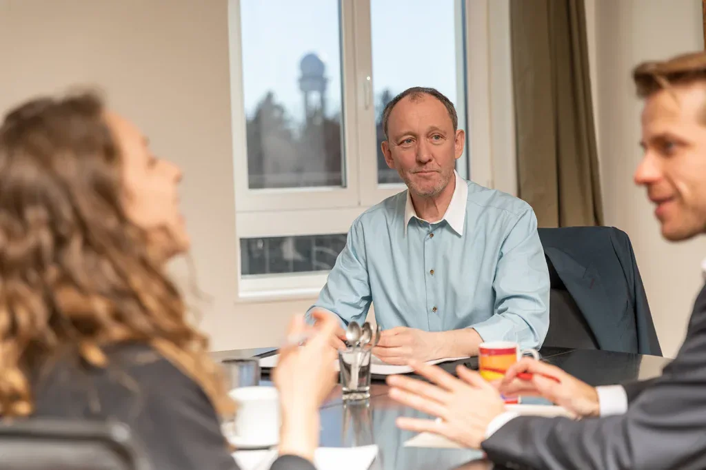 Drei Personen führen ein persönliches Beratungsgespräch an einem Besprechungstisch.