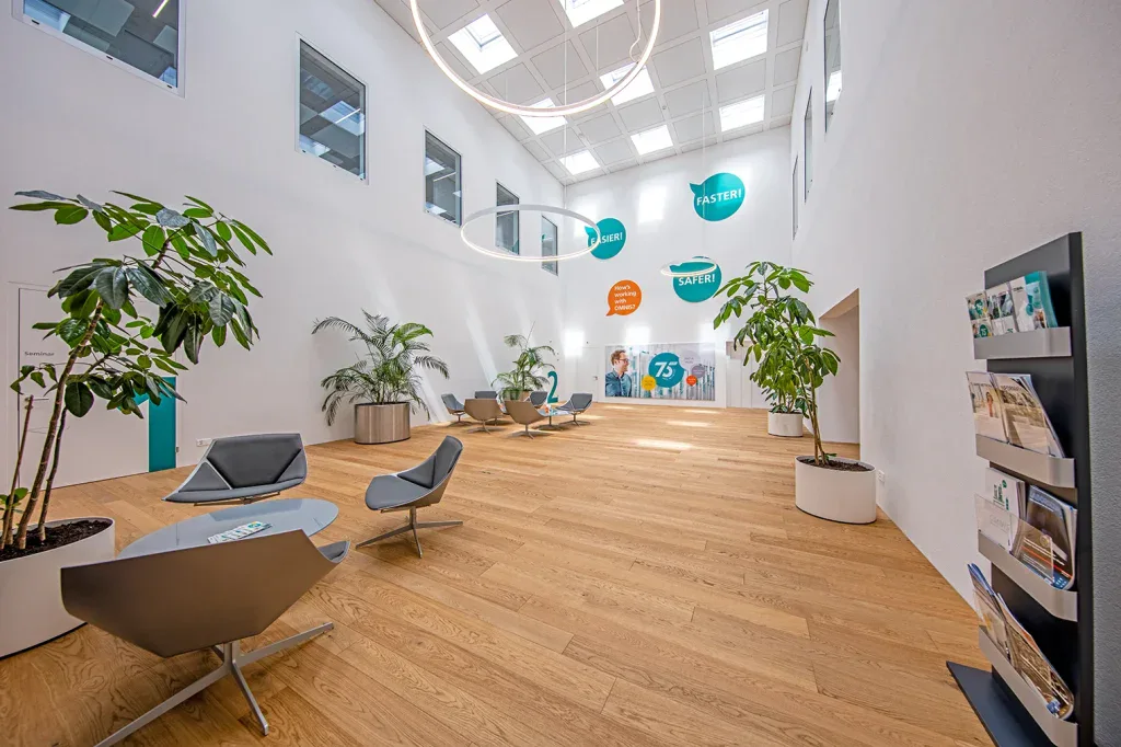Offener Empfangsbereich mit Sitzgruppen, Pflanzen und hohem Atrium in einem Unternehmen in Zofingen.
