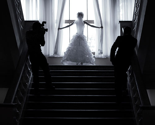 Braut im Hochzeitskleid vor einem grossen Fenster während eines Hochzeitsshootings im Treppenhaus